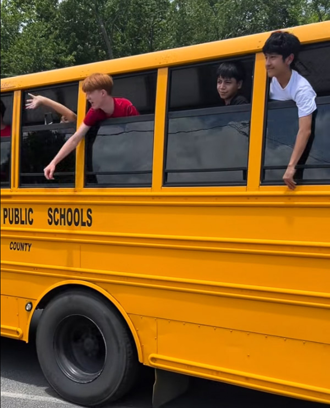 Students waive as the school bus pulls away on the last day of the year.