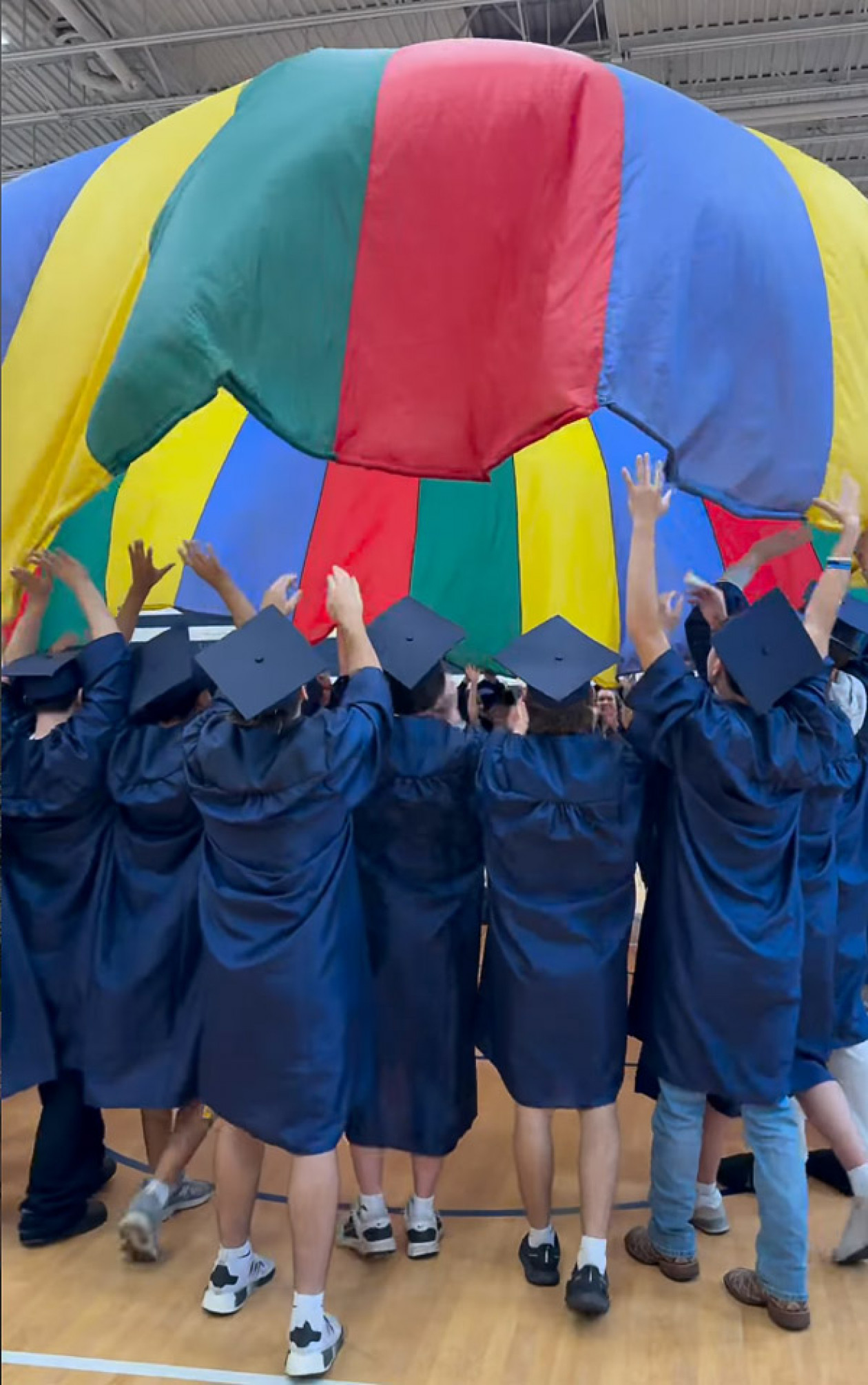 Enka High School graduates get under a parachute at an elementary school.
