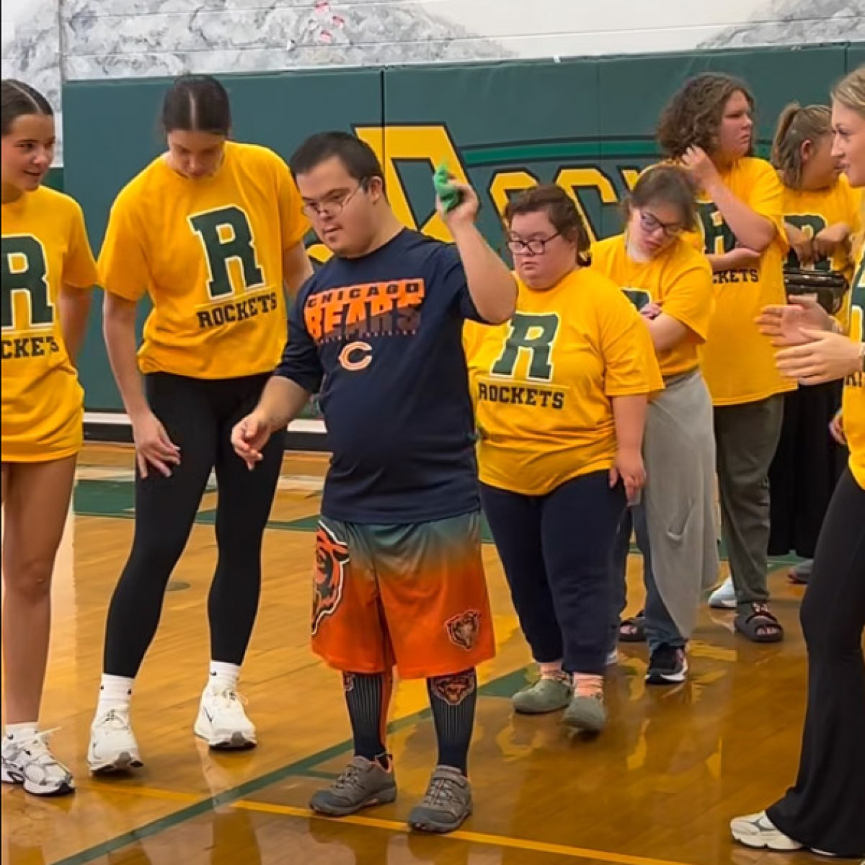 A student gets ready to throw a beanbag surrounded by students wearing yellow Reynolds Rockets shirts.