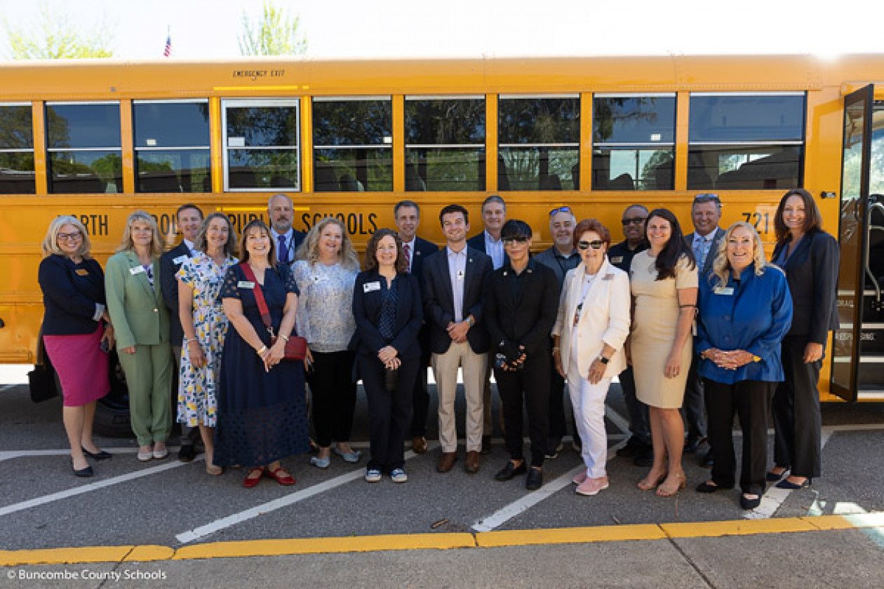 Elected leaders and BCS leadership staff pose in front of a school bus.