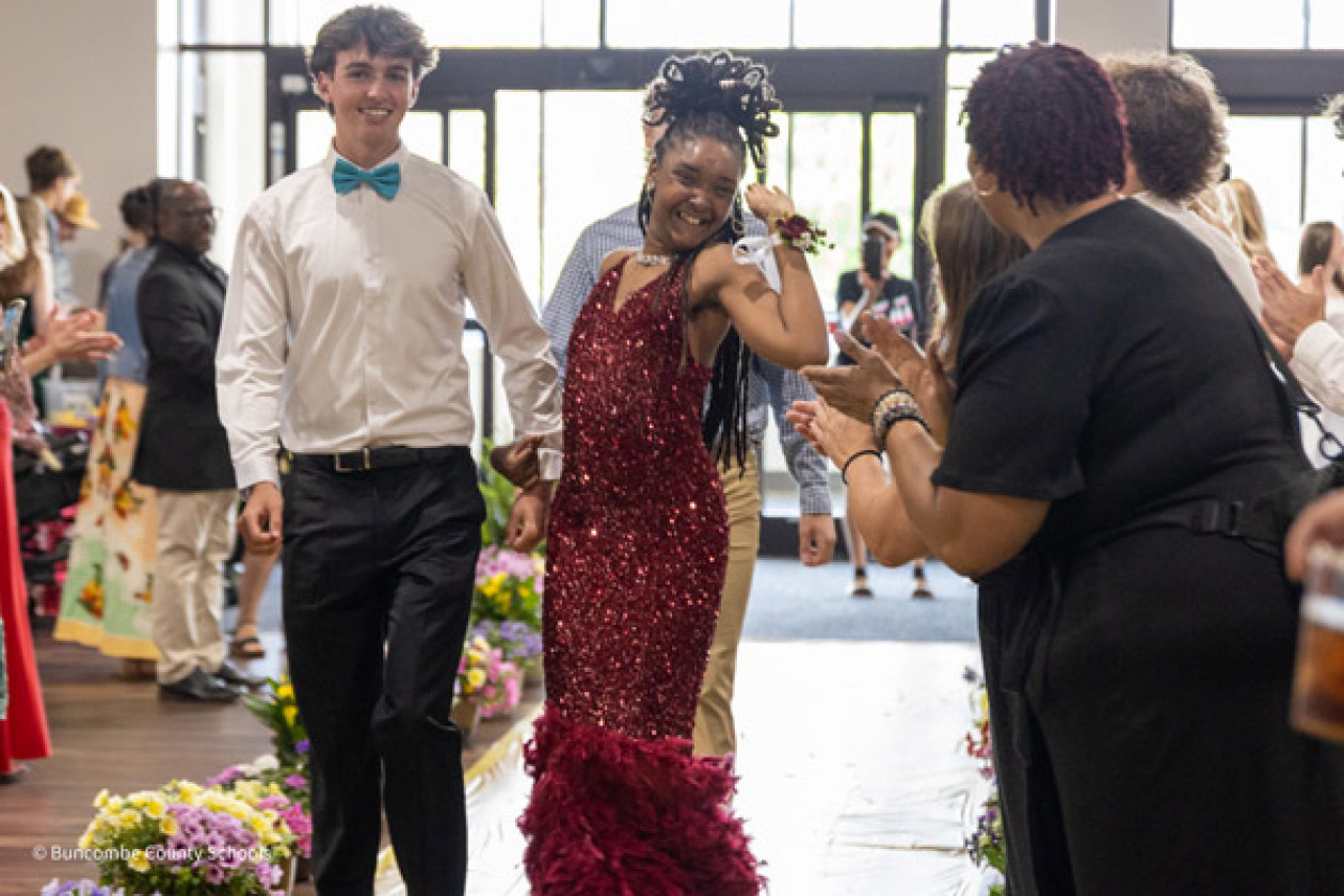 A PEP student, wearing a red dress, and her escort smile at the event.