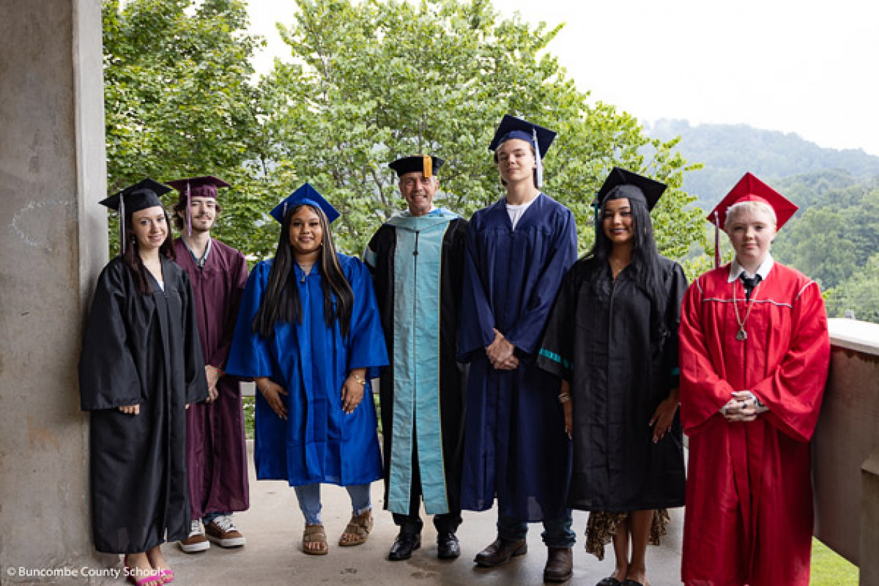 Dr. Jackson poses with graduates in caps and gowns of the colors of BCS high schools.