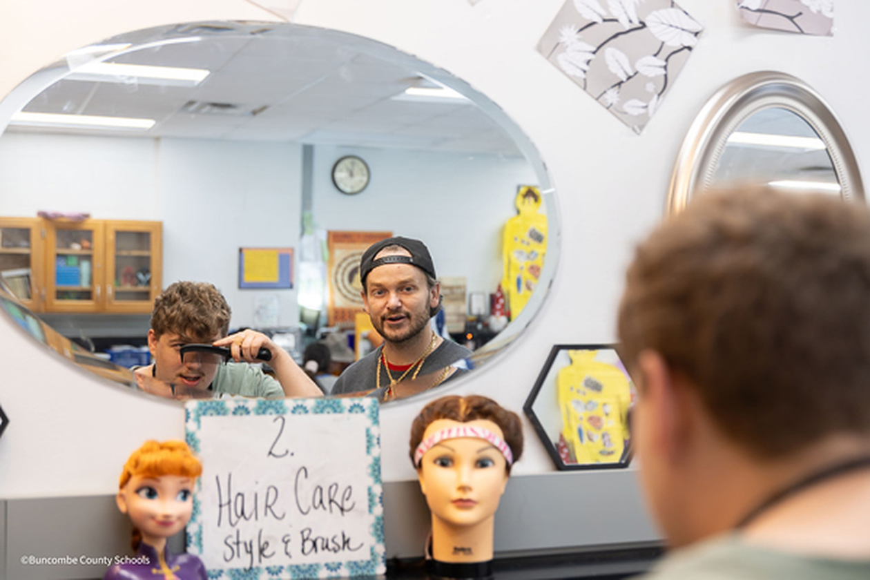 Tyler Plemmons watches in a mirror as a student combs his hair.