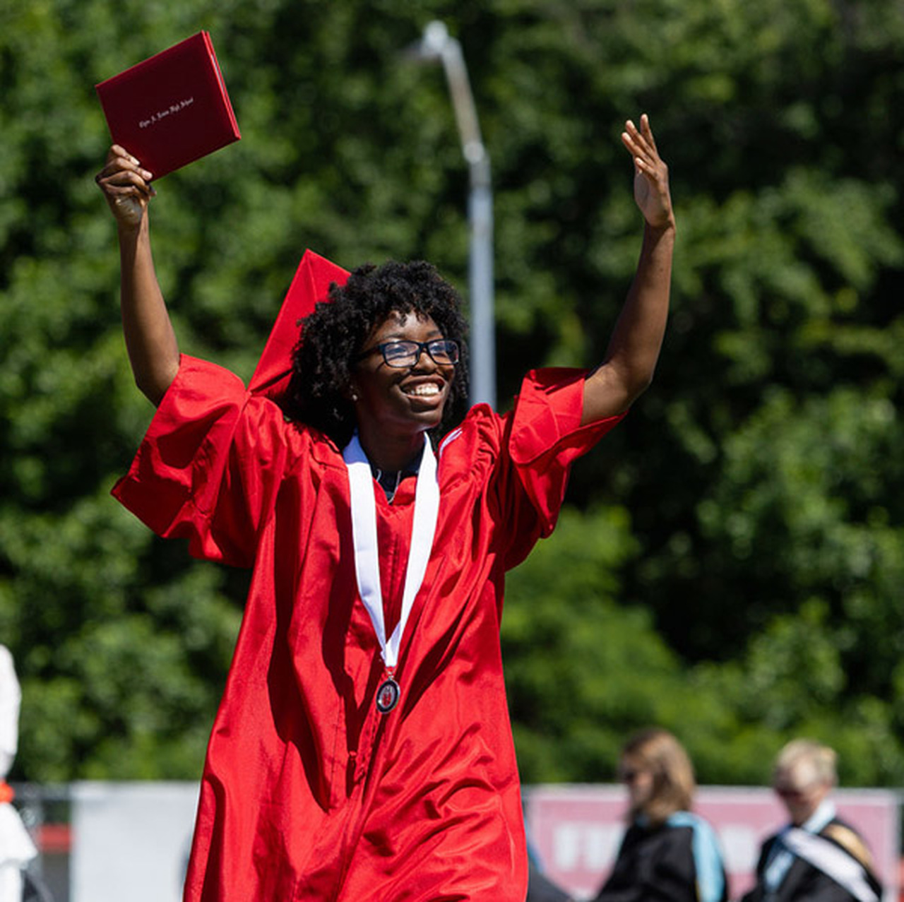 An Erwin High graduate raises her arms and smiles.