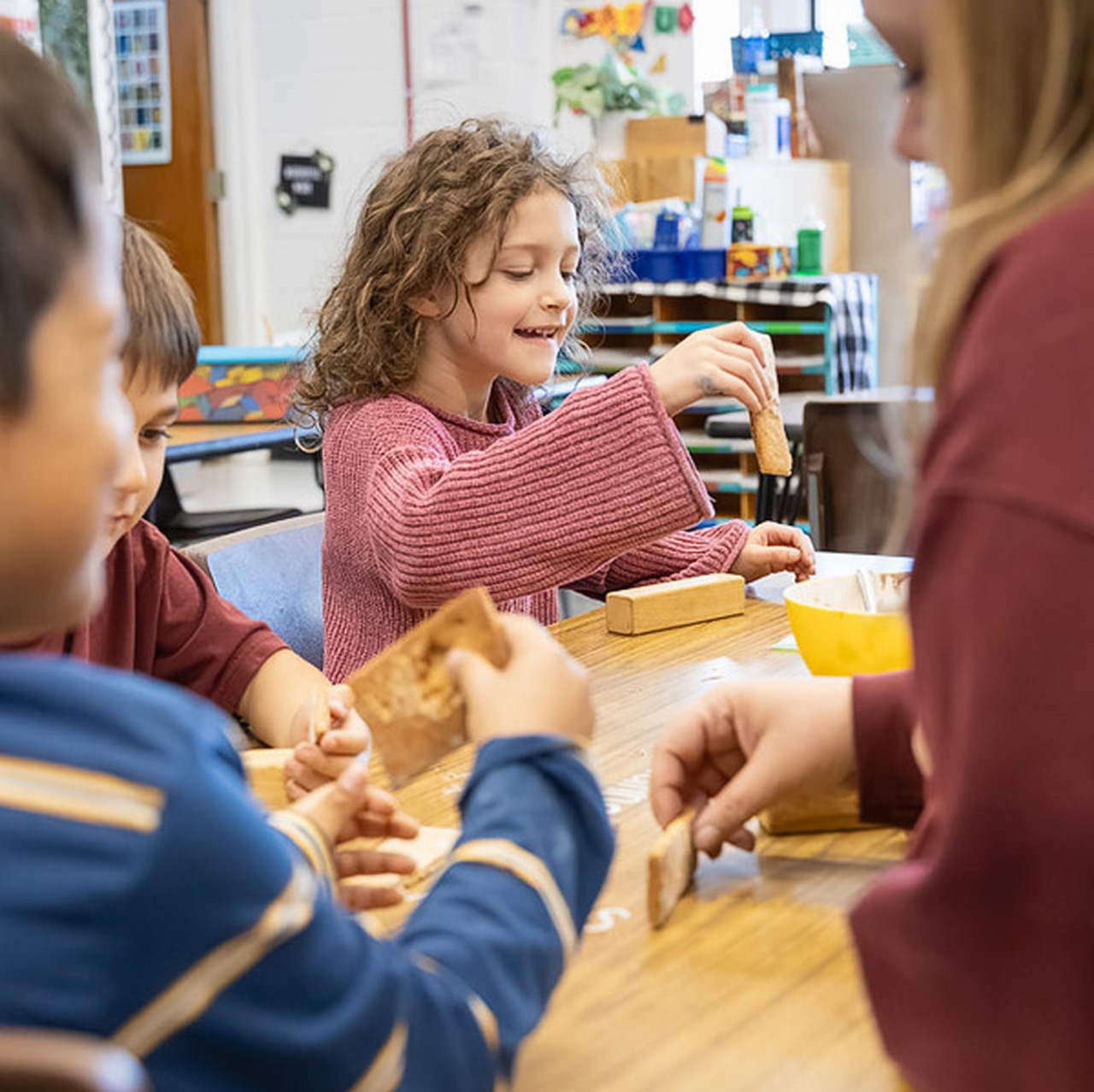 A student works with a piece of gingerbread at a table.
