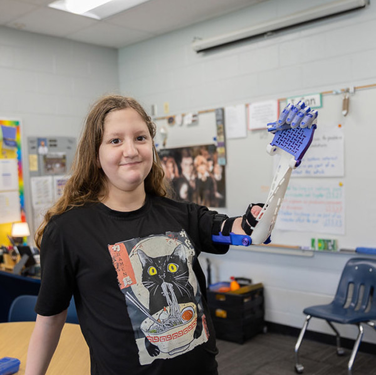 A student shows off her prosthetic arm in a classroom.