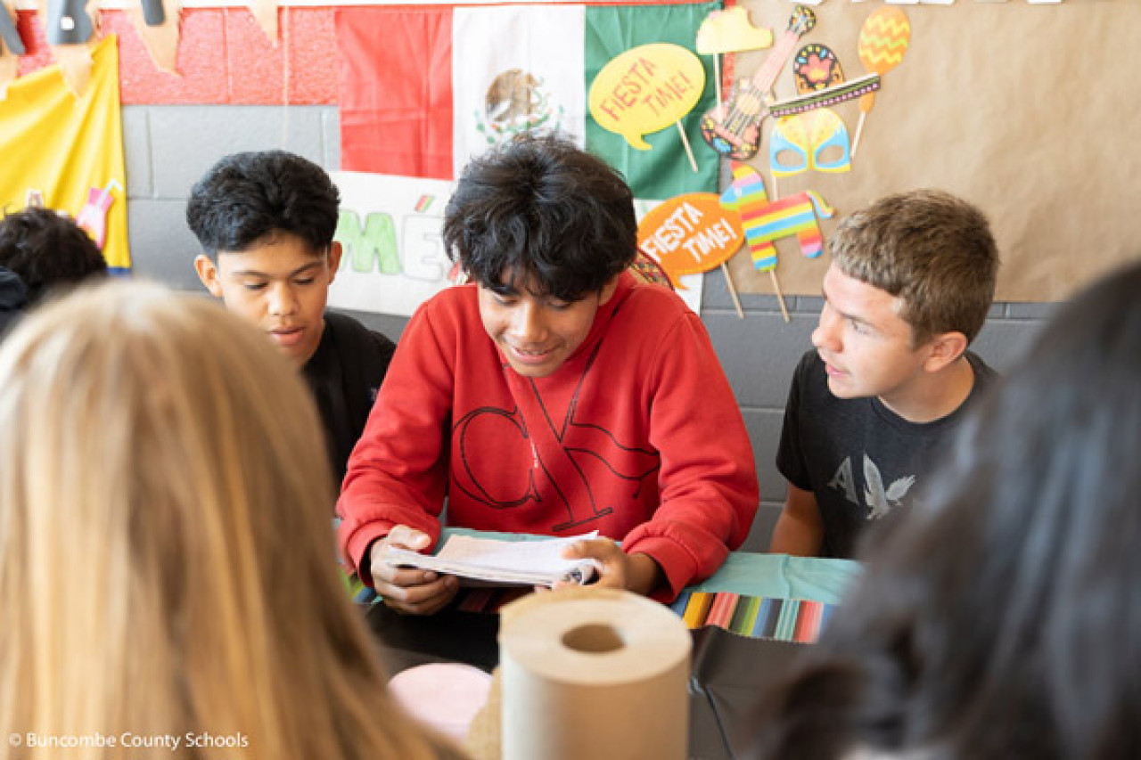 A student smiles while reading to other students.
