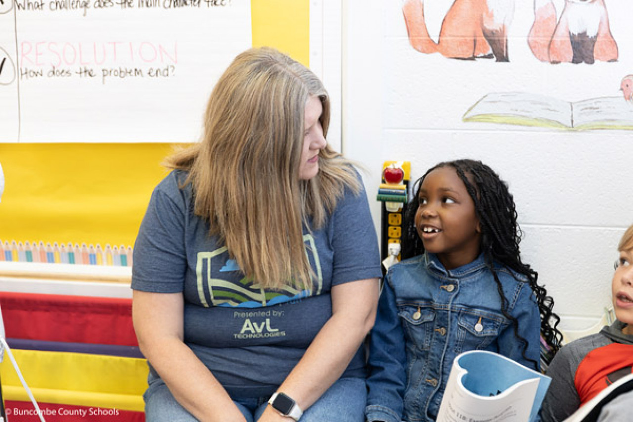 Woodfin Elementary School principal Miranda Wheeler talks to a girl in a classroom.