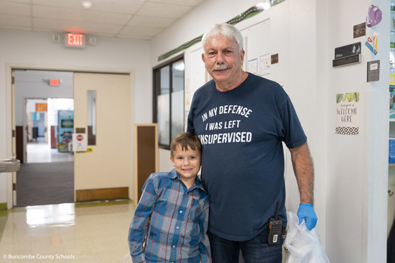 Mike Allison poses with a student in a school hallway.