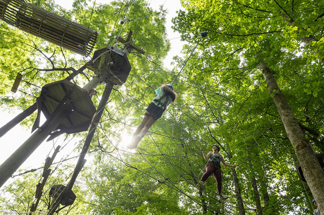 A student uses a zip line to cross part of a ropes course at Nantahala Outdoor Center.