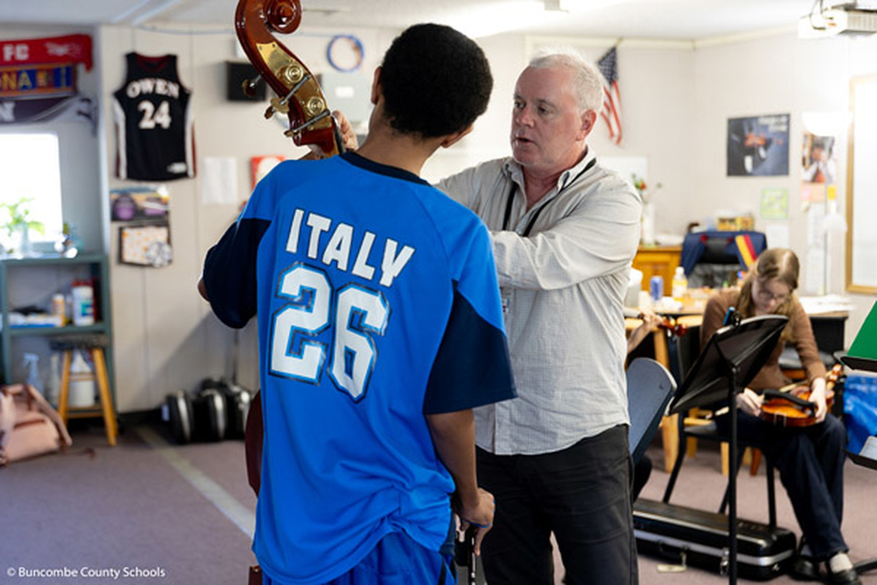 Matthew Kinne helps a student with an upright bass.
