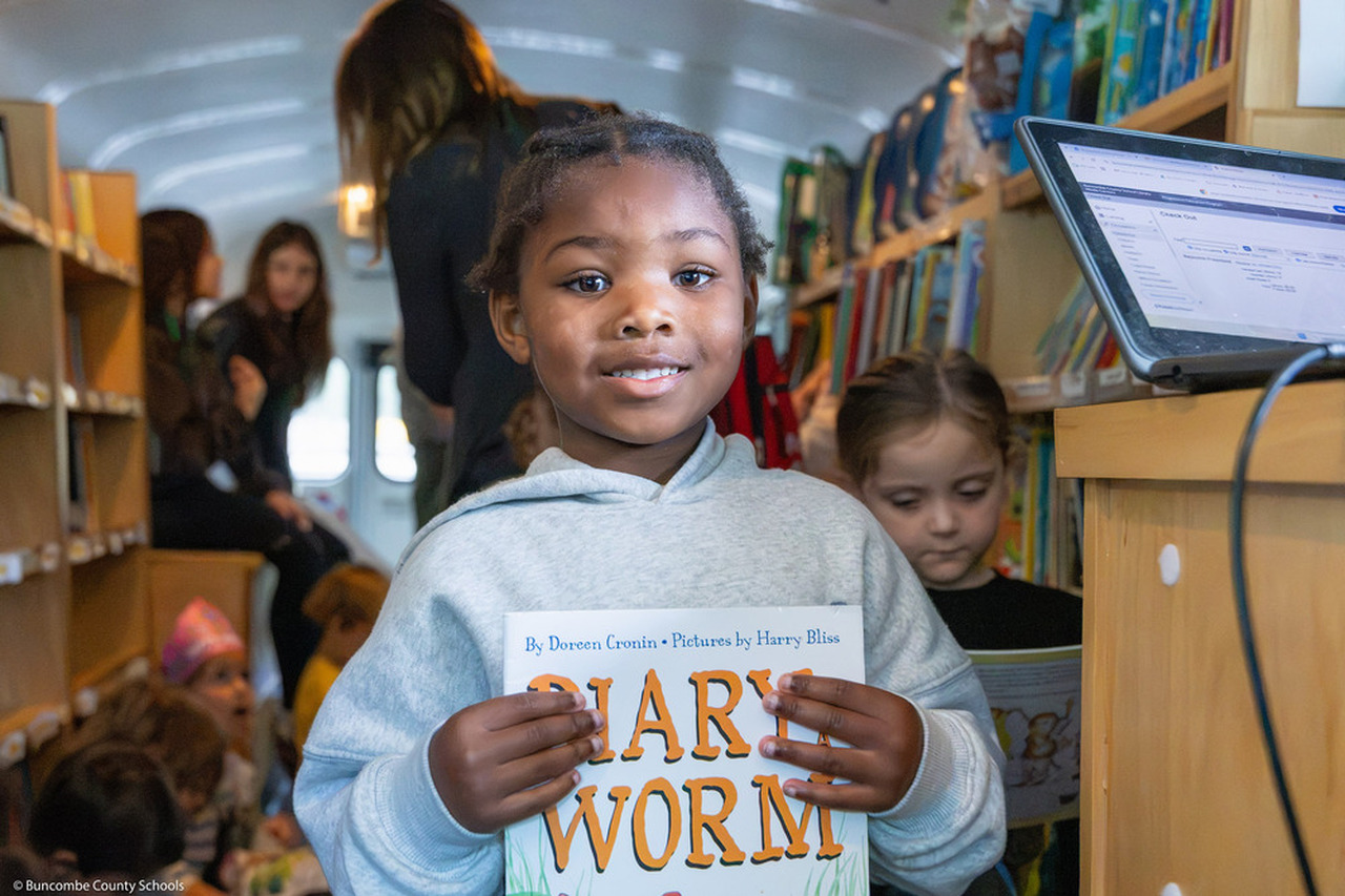 A girl smiles with holding a book.
