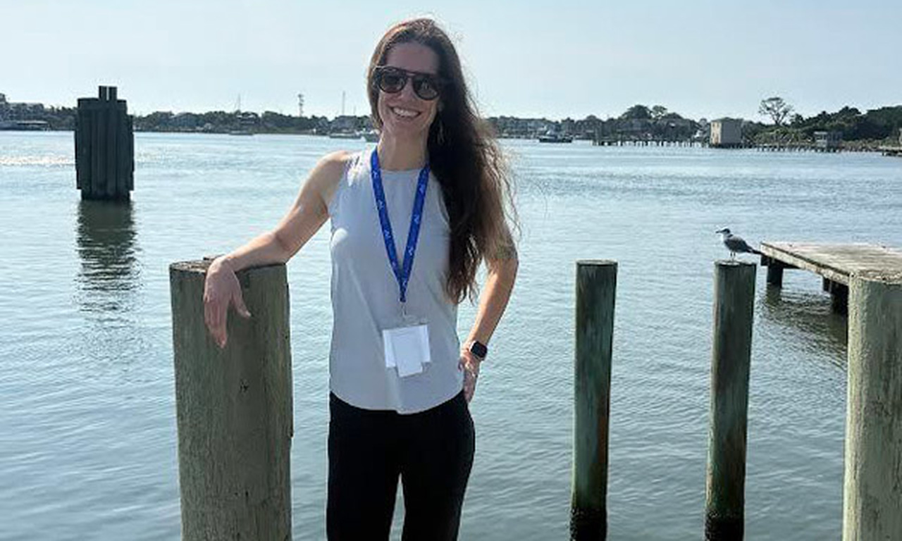 Katie Wilson poses at the end of a pier in the sunlight.