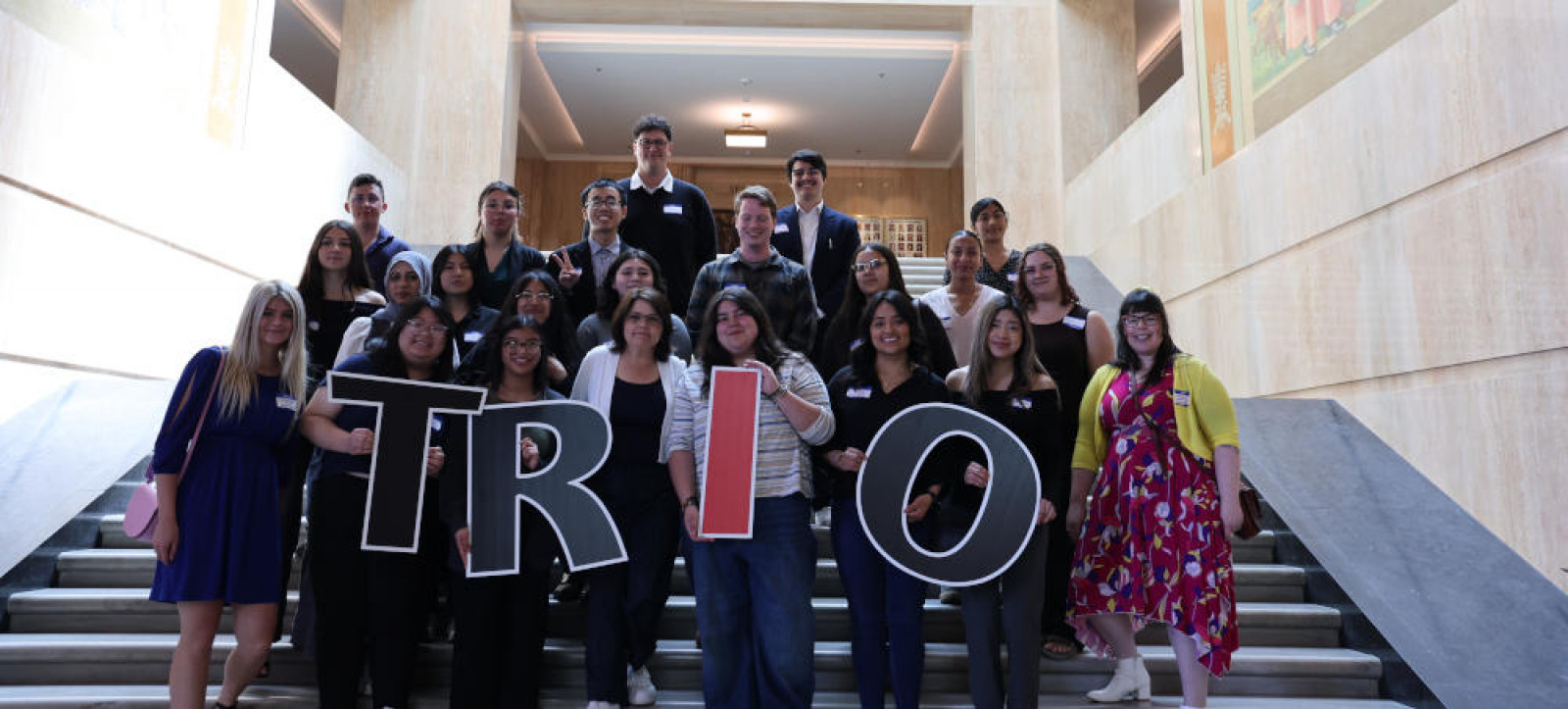 Students posing on the steps inside the Oregon Capitol with large TRIO letter cutouts.