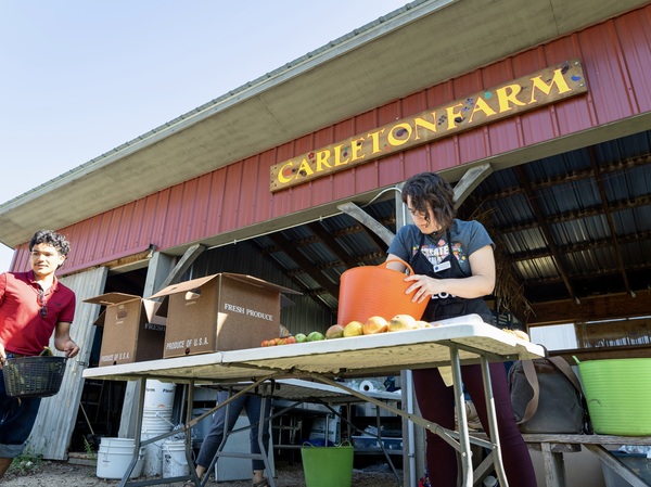 Two students fill buckets at the Carleton farm
