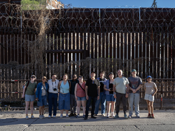 Trip members pose for the camera in front of a tall fence