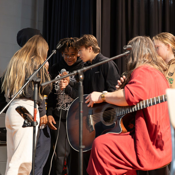 Students gather around a mic to sing at Reynolds Middle.