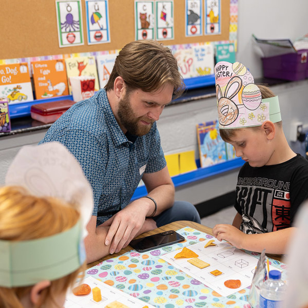 A man and a boy lean over a project that matches food items with shapes.
