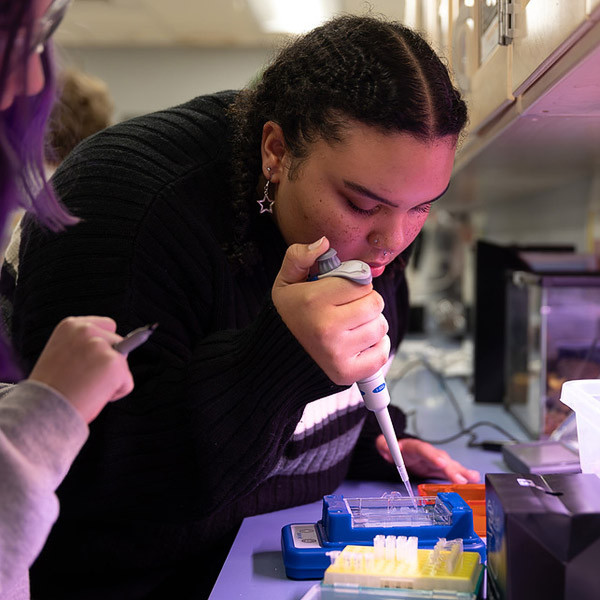 A student uses lab equipment to collect a sample.