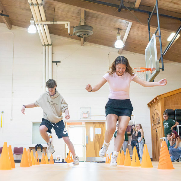 Two students run through cones as part of an obstacle course.