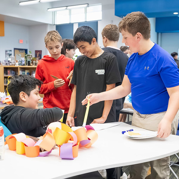 Four students smile while bartering at a table.