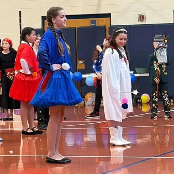 Students perform while dressed in colorful costumes.