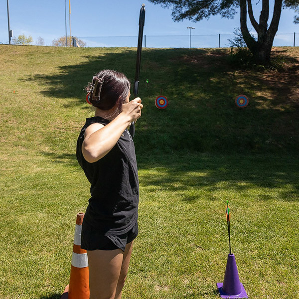 A student shoots an arrow at a target.