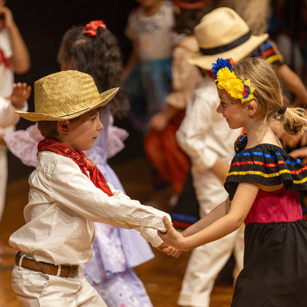 A boy and a girl, both wearing traditional clothing, dance at the event.
