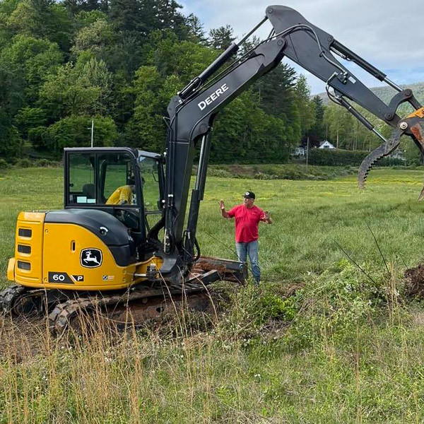 A student operates a back hoe while an adult instructs.