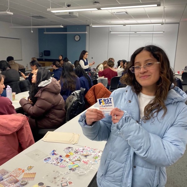 Student poses with First Gen sticker at Writing Home event