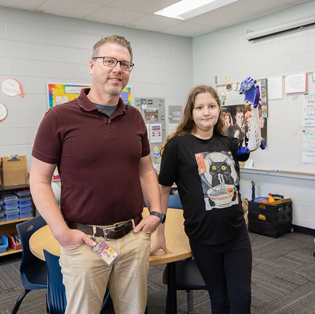 North Windy Ridge Intermediate School STEM teacher Russell Thompson poses with a fifth grade student wearing the prosthetic arm. 
