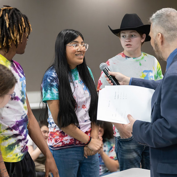 A student smiles while speaking into a microphone.