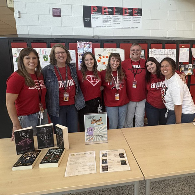 Seven Erwin High teachers pose in front of a Book Club table.