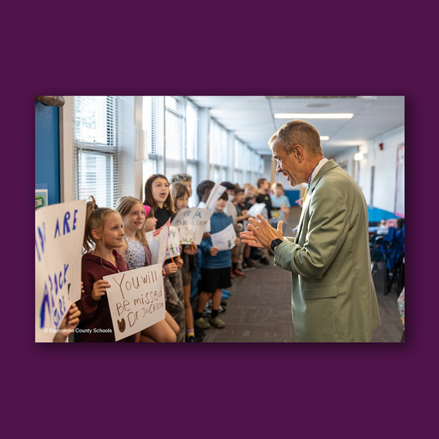 Dr. Jackson claps while facing a student with a sign that says 