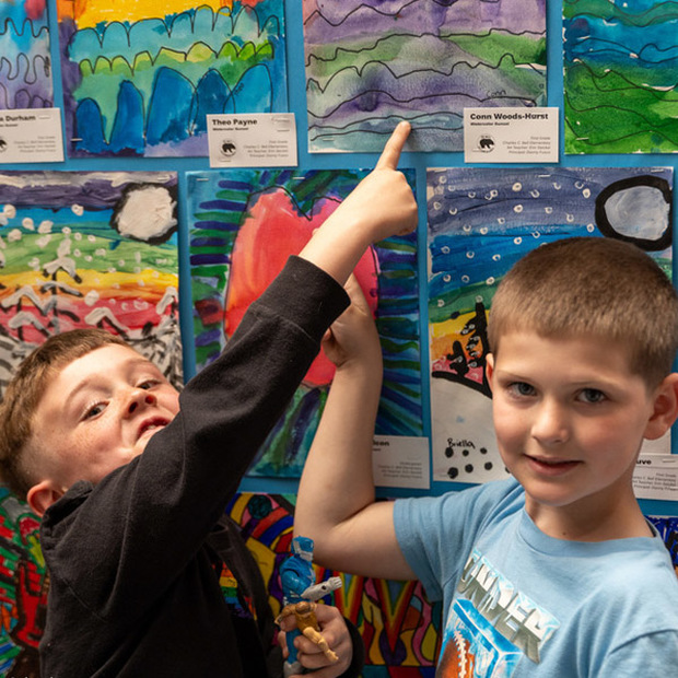 Two students point at their artworks at the mall.