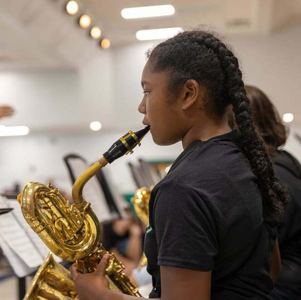 A girl plays saxophone in band class.