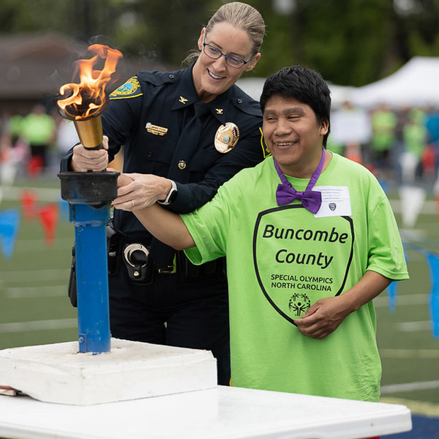 A student and SRO light the ceremonial torch at the Special Olympics.
